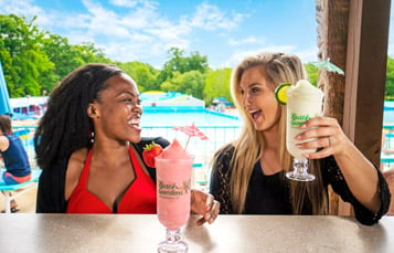 Guests talking over frozen cocktails with the Surfer's Bay wave pool in the background